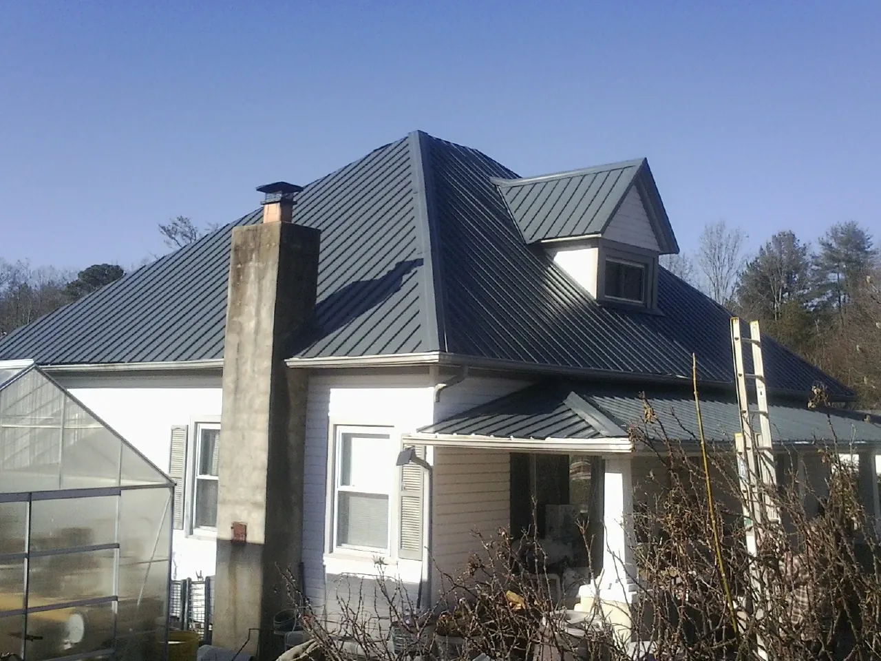 Dark blue standing seam metal roof on a white farmhouse with dormer — Slate & Tile Roof Repair by Roofing Brothers in Tulare