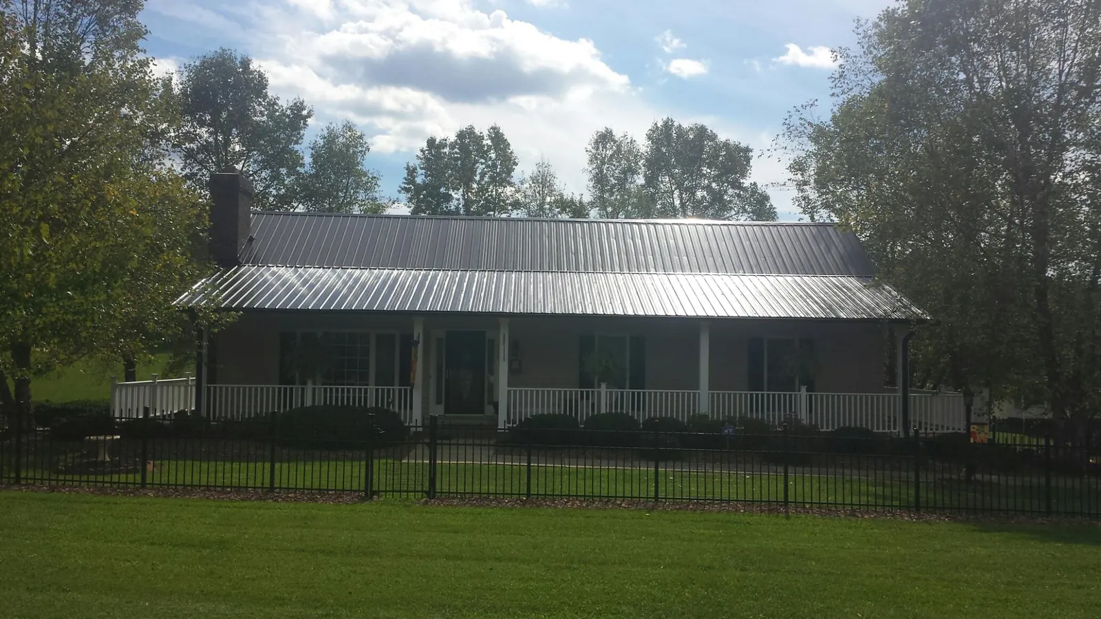 Gray metal roof on a brick ranch with a full width front porch — Gutter Guard Installation work by our crew in Tulare