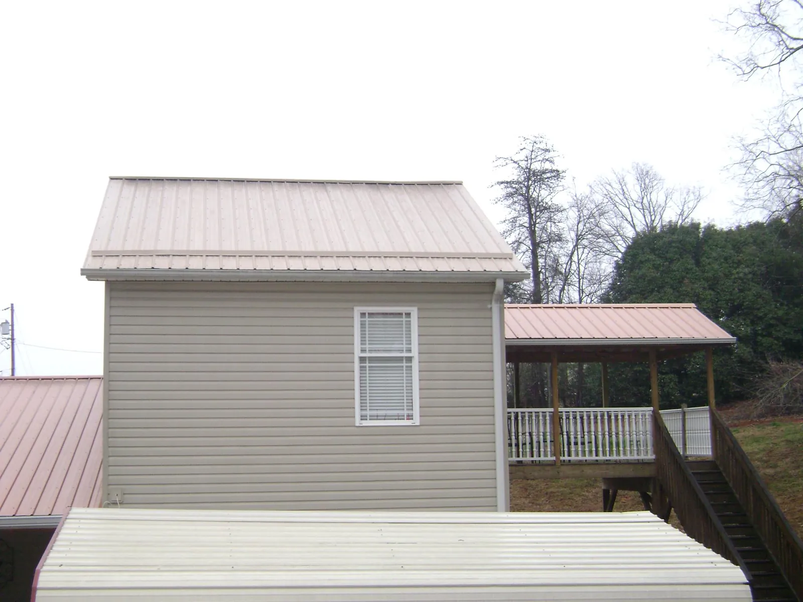 Tan metal roofs on a two story addition and attached porch, from a Roof Replacement job in Tulare
